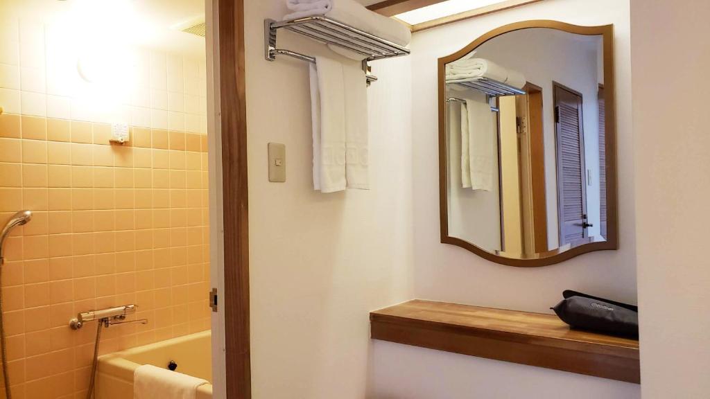 AoAwo Naruto Resort — bathroom interior featuring a vanity mirror, wooden shelving, and a separate bathtub area with warm yellow tiling.