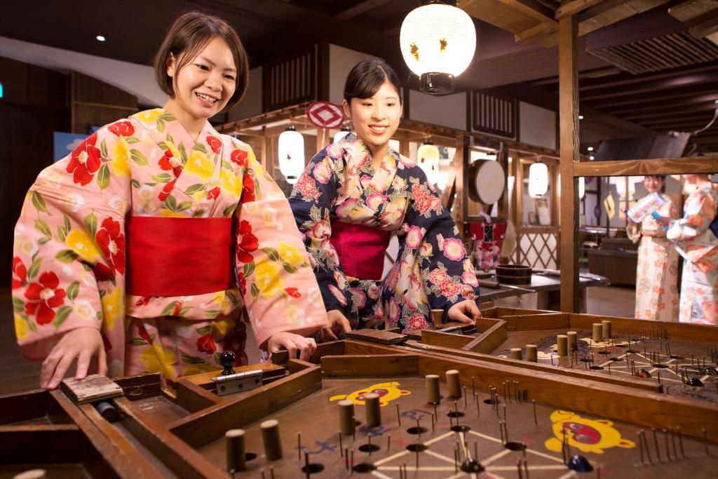 AoAwo Naruto Resort — interior view of the Awa Market entertainment area with guests enjoying traditional wooden pinball and festival activities.