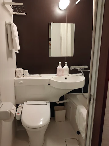 Business Hotel Pocket — compact modular unit bath featuring a Japanese electronic bidet toilet, washbasin, and bathtub with complimentary toiletries in Matsushige, Tokushima. | Hotel Manga