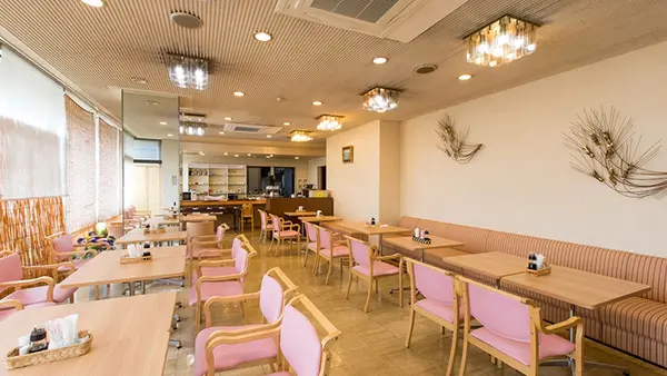 Business Hotel Pocket — bright and spacious dining hall featuring light wood tables, pink upholstered chairs, and a breakfast buffet area for guests in Matsushige, Tokushima. | Hotel Manga