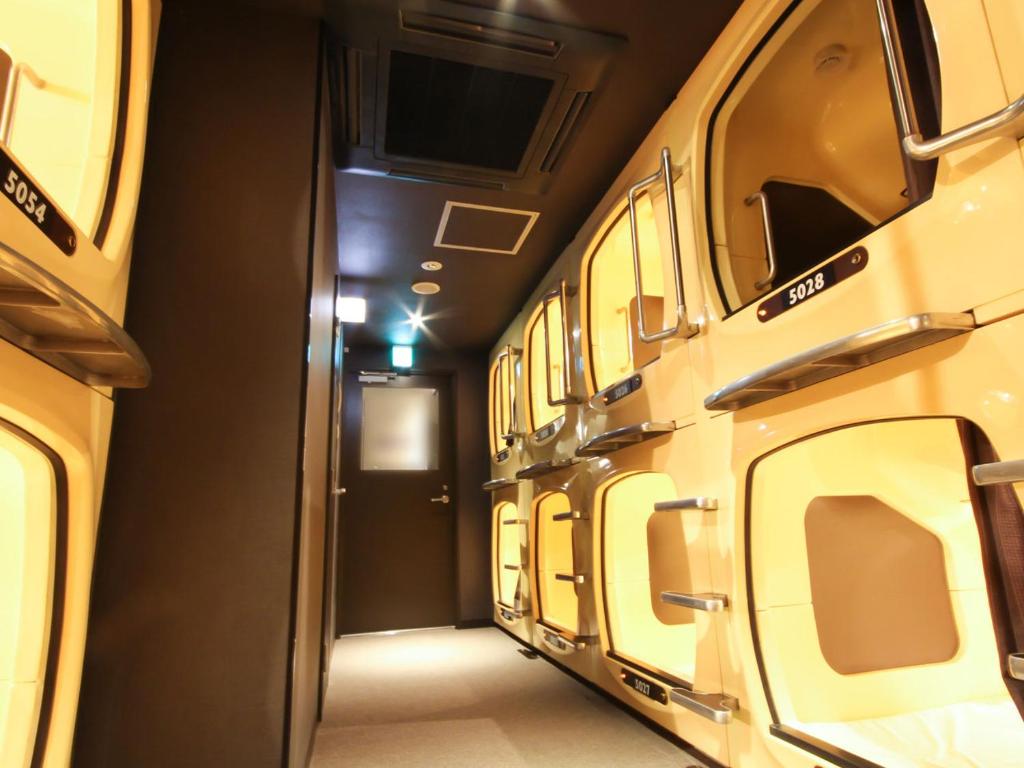 Grancustoma Ueno - Perspective view of the capsule hotel floor with illuminated sleeping units.