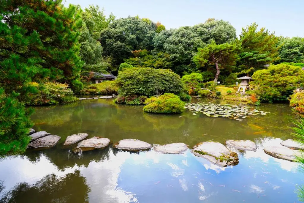 Daimaru Besso 大丸別荘 — traditional Japanese stroll garden with stone pathways, seasonal greenery, and the historic inn buildings visible in the background | Hotel Manga