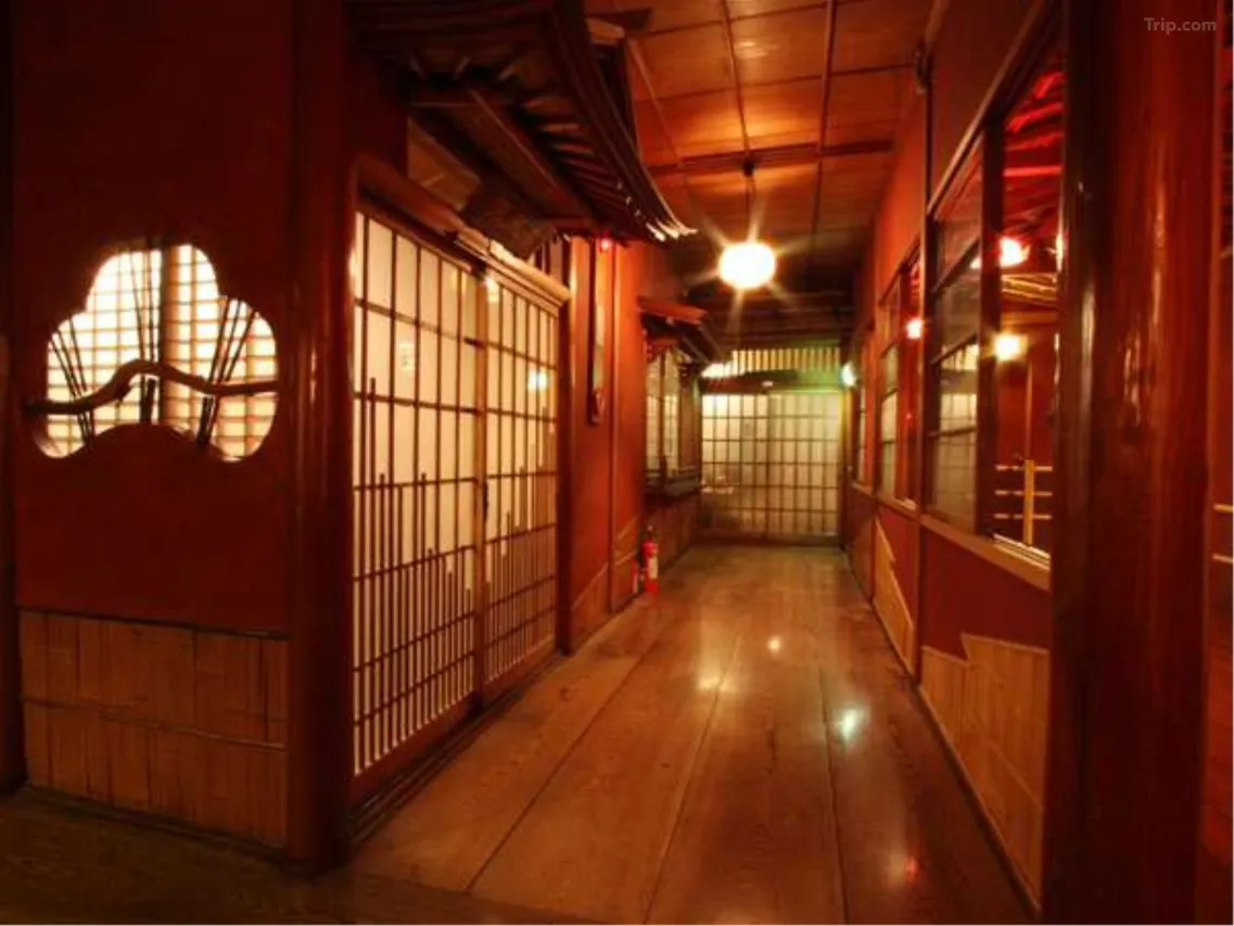 Narrow lantern-lit corridor inside Rekishi-no-Yado Kanaguya ryokan — curved staircase and carved wooden panels