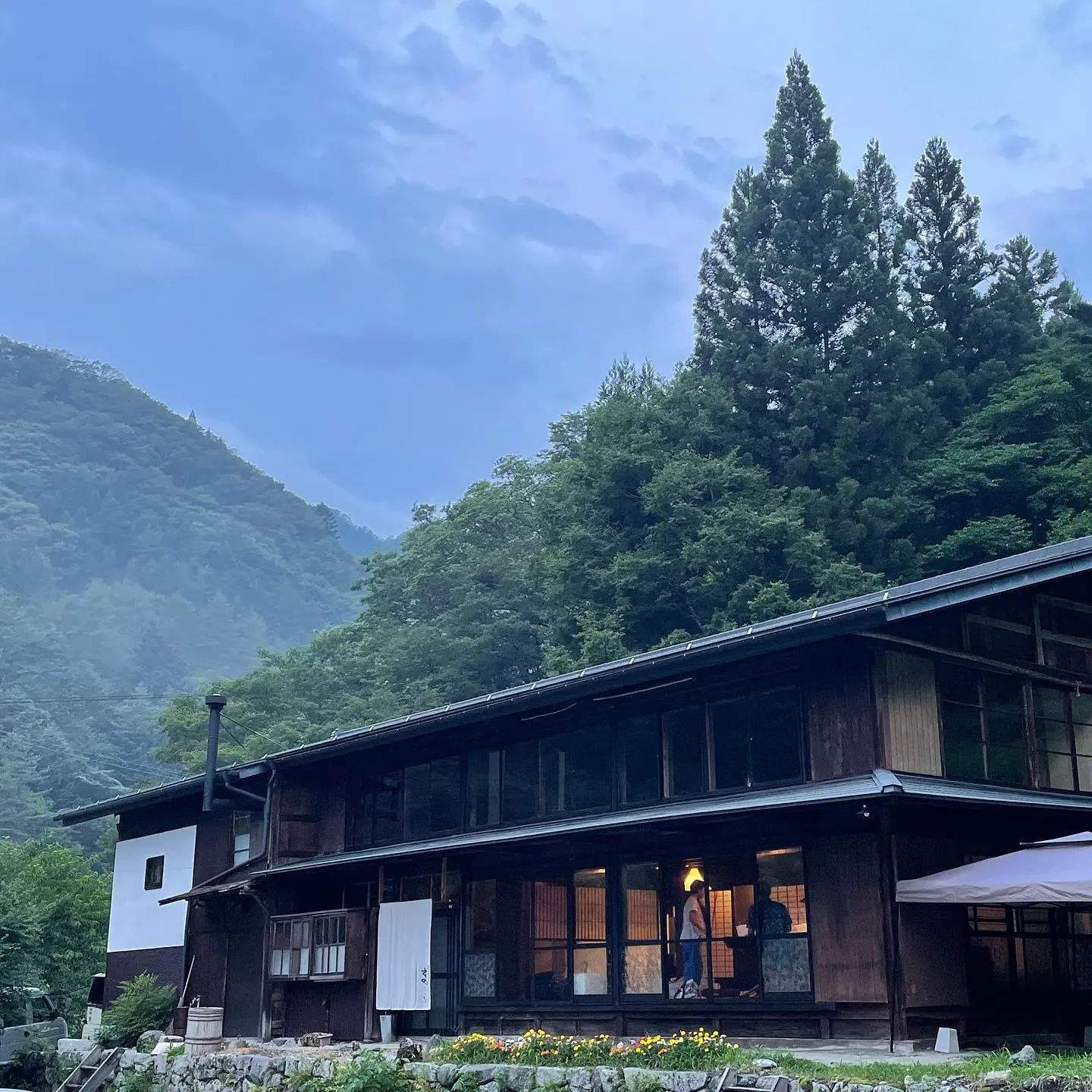 Magokoro kominka exterior — 190-year-old single-storey wooden farmhouse in Kamimura Iida with mountain backdrop
