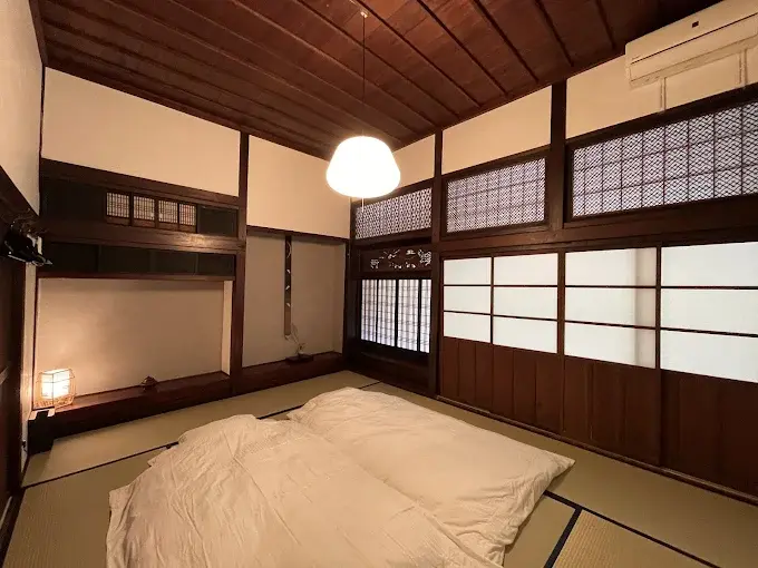 Magokoro 190-year-old kominka exterior in Kamimura Iida — single-storey wooden farmhouse with mountain backdrop