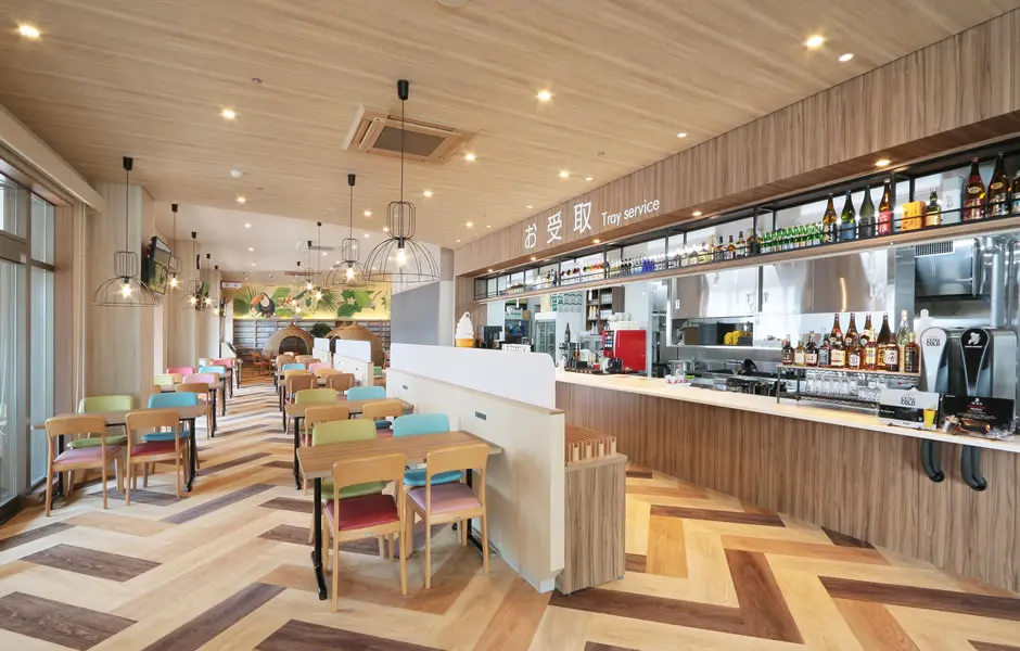 Teriha Spa Resort 照葉スパリゾート — bright and modern restaurant with colorful seating, wood-patterned flooring, and a tray-service bar counter in Higashi-ku. | Hotel Manga