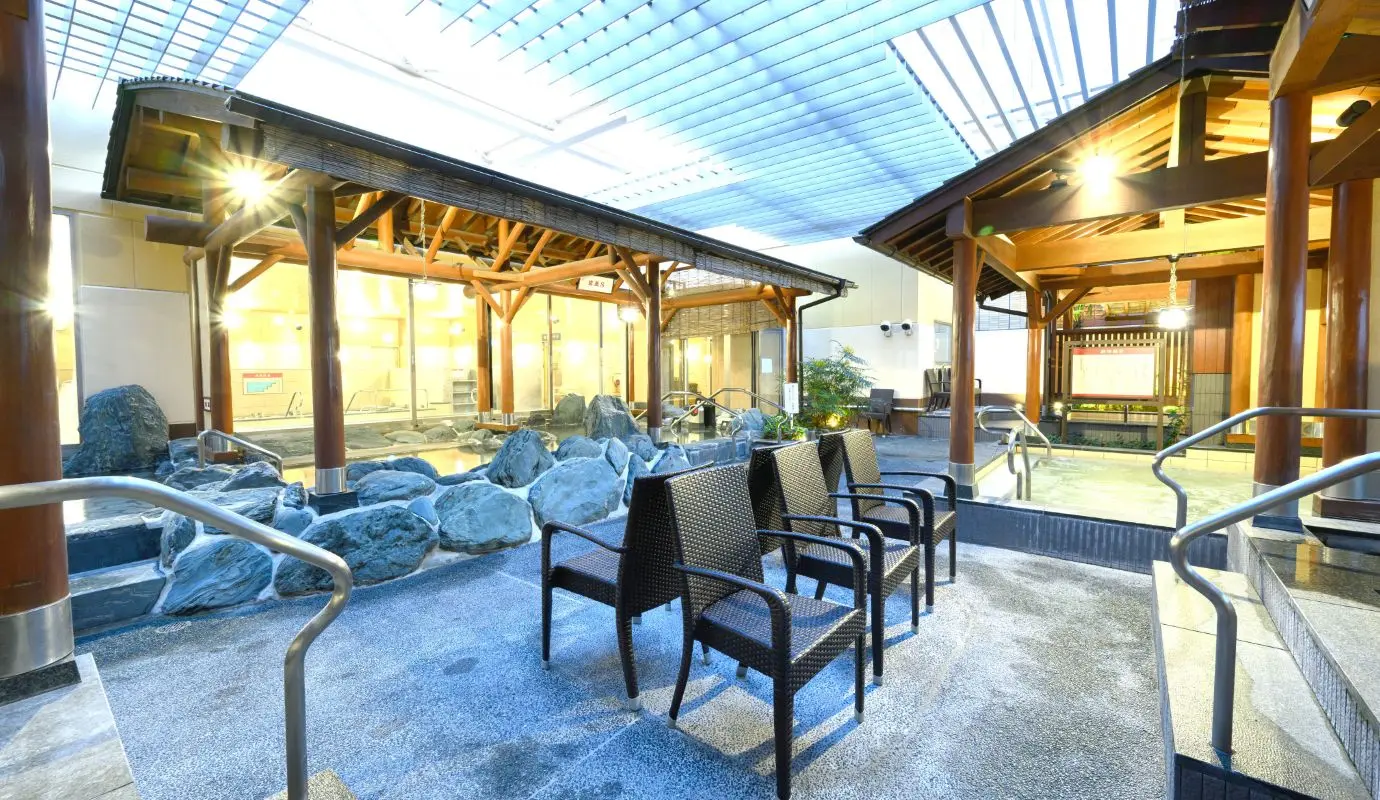 Teriha Spa Resort 照葉スパリゾート — spacious outdoor hot spring (rotenburo) with natural rock pools and traditional wooden gazebos under a slatted roof. | Hotel Manga